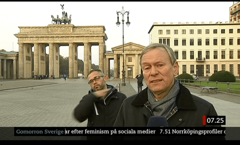 migrant slitting throat behind reporter.png